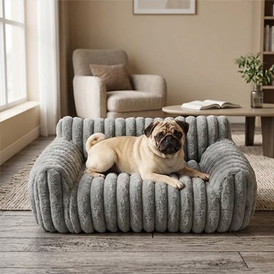 Carlin installé dans un canapé pour chien gris en peluche rayée, dans un salon