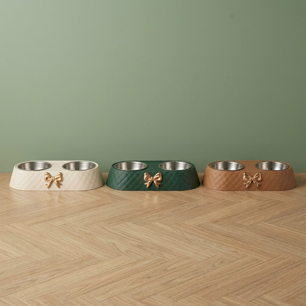Gamelle pour chien double bol inox à nœud doré en blanc, vert et marron, posées côte à côte sur un parquet