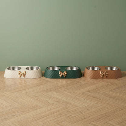 Gamelle pour chien double bol inox à nœud doré en blanc, vert et marron, posées côte à côte sur un parquet