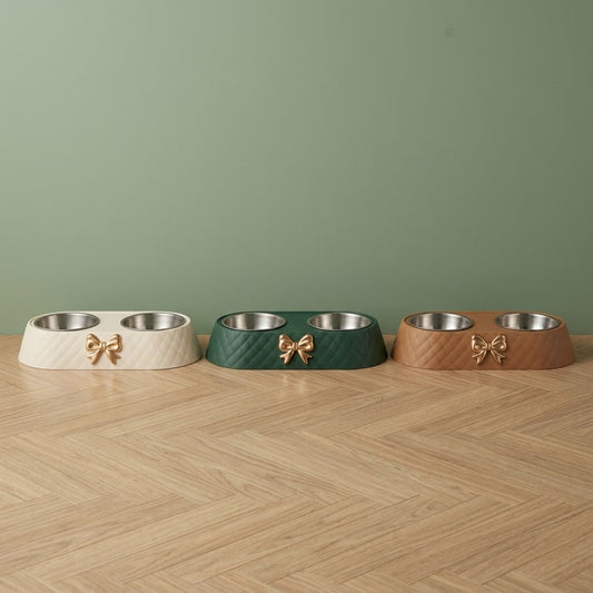 Gamelle pour chien double bol inox à nœud doré en blanc, vert et marron, posées côte à côte sur un parquet