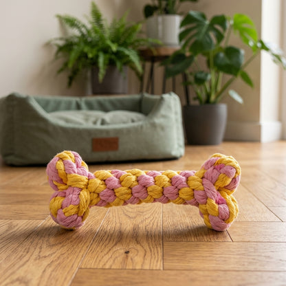 Os en corde pour chien tressé en coton rose et jaune, posé sur un parquet