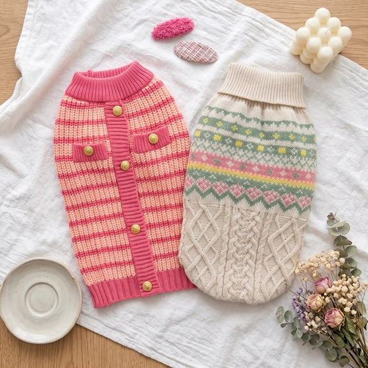 Pull pour chien en tricot : pull rose à rayures et pull beige torsadé posés à plat
